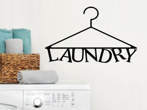 Laundry room wall decal that says ‘Laundry (Clothes Hanger)’ in a print font on a laundry room wall.