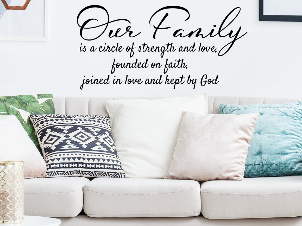 Living room wall decals that say ‘Our family is a circle of strength and love, founded on faith, joined in love and kept by God’ on a living room wall. 