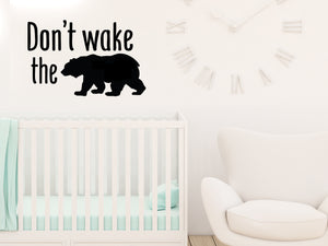 Wall decal for kids that says ‘Don't Wake The Bear’ in a print font on a kid’s room wall. 
