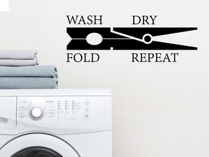 Laundry room wall decal that says ‘Wash Dry Fold Repeat (ClothesPin)’ on a laundry room wall.