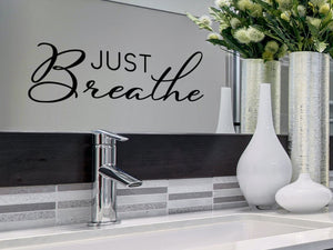 Wall decals for bathroom that say ‘Just Breathe’ in a script font on a bathroom mirror.