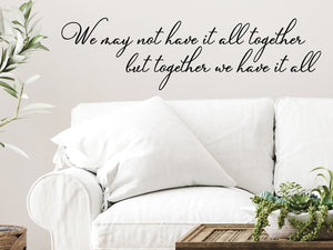 Living room wall decals that say ‘We May Not Have It All Together But Together We Have It All’ in a cursive font on a living room wall. 