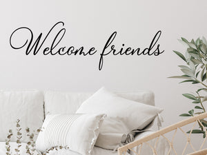 Living room wall decals that say ‘Welcome Friends’ in a cursive font on a living room wall. 