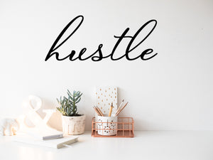 Wall decal for the office that says ‘Hustle’ in a cursive font on an office wall.