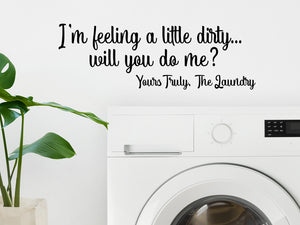 Laundry room wall decal that says ‘I'm Feeling Dirty Will You do Me? Yours Truly The Laundry’ in a script font on a laundry room wall.