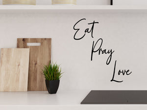 Wall decals for kitchen that say ‘Eat Pray Love’ in a cursive font on a kitchen wall.