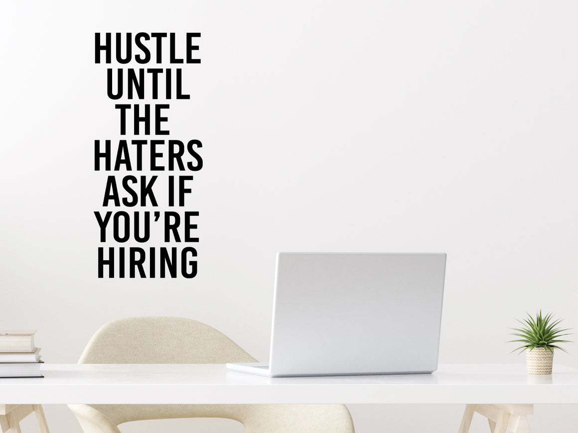 Wall decal for the office that says ‘Hustle Until The Haters Ask If You're Hiring’ in a bold font on an office wall.