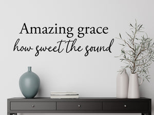 Living room wall decals that say ‘Amazing Grace How Sweet The Sound’ in a script font on a living room wall. 