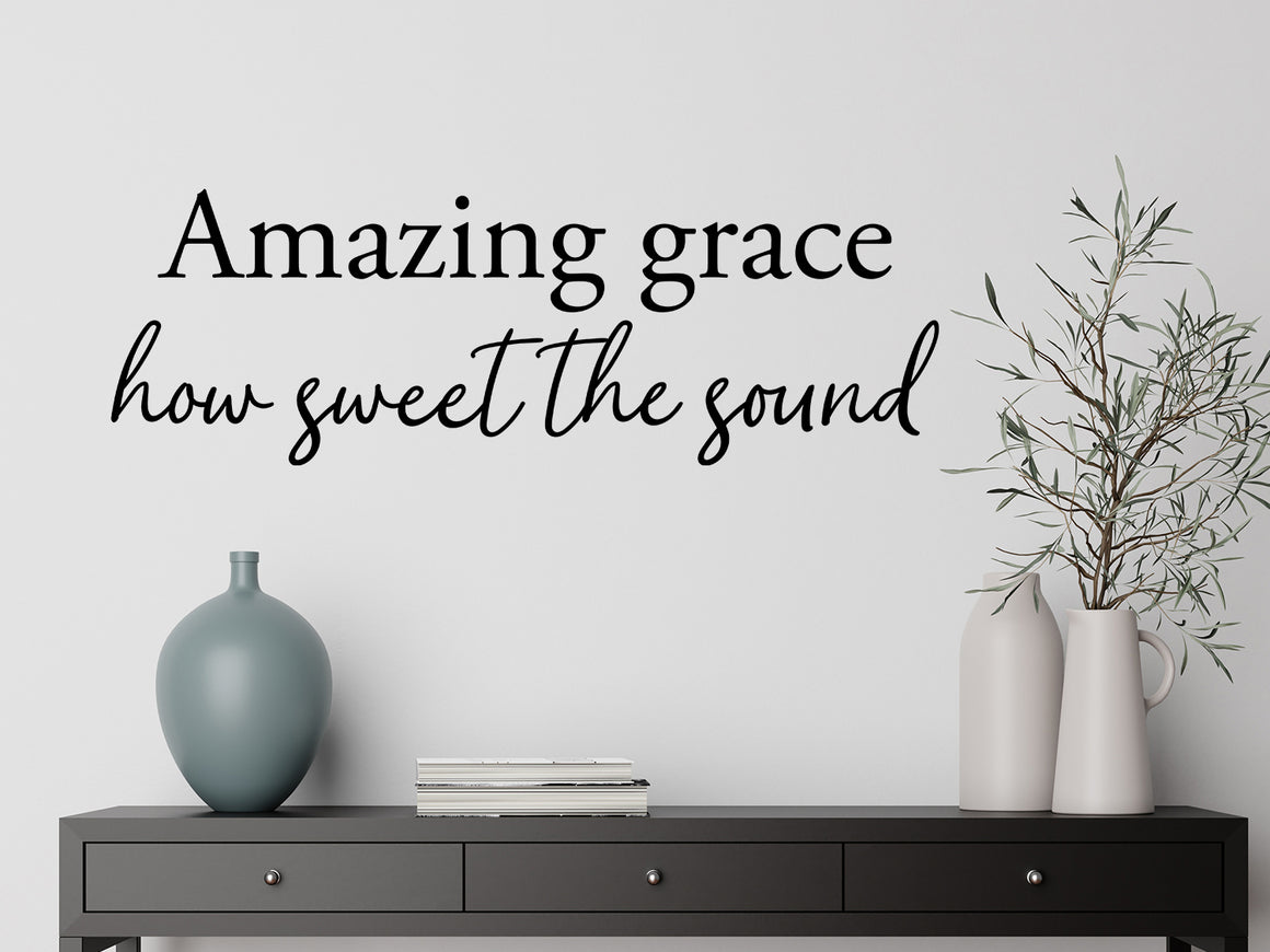 Living room wall decals that say ‘Amazing Grace How Sweet The Sound’ in a script font on a living room wall. 