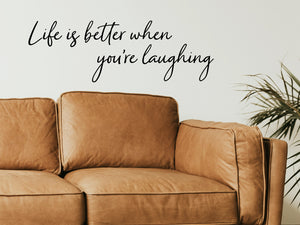 Living room wall decals that say ‘Life Is Better When You're Laughing’ in a cursive font on a living room wall. 