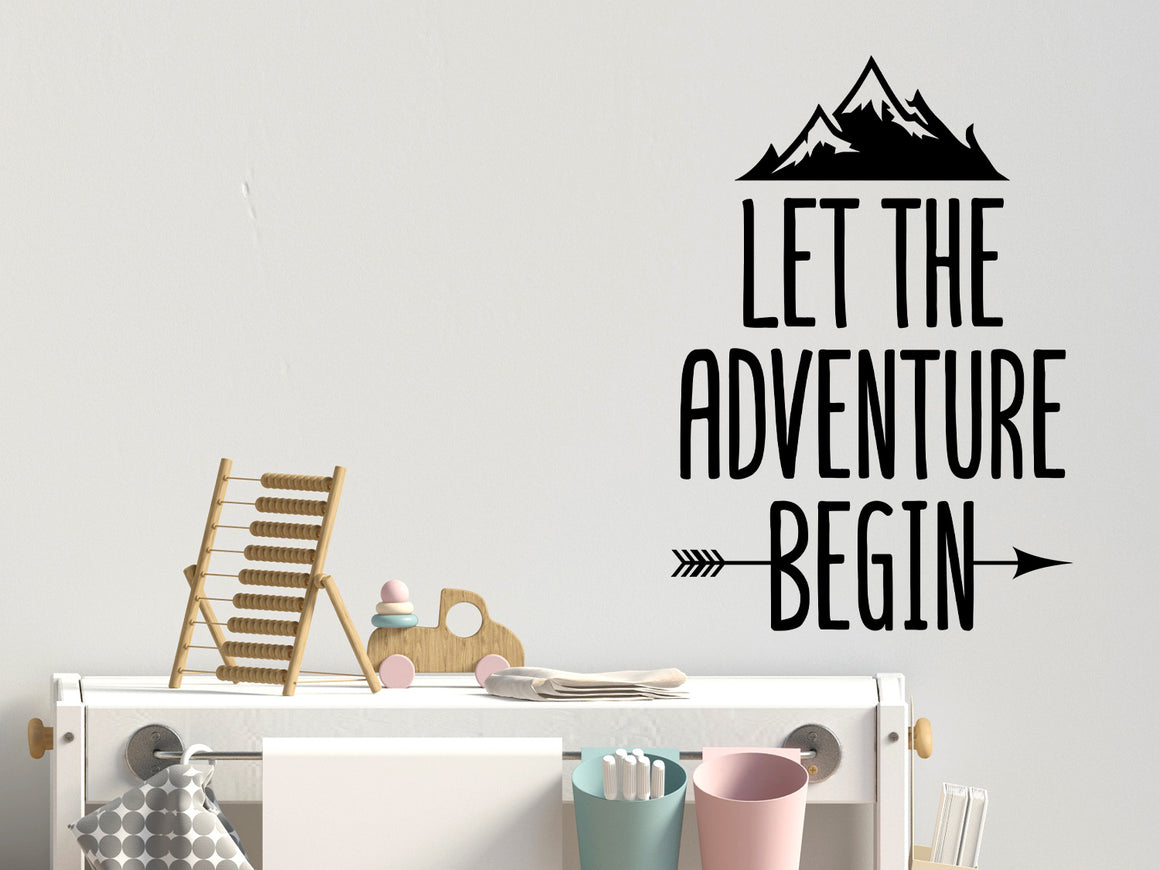 Wall decal for kids that says ‘Let The Adventure Begin’ with an arrow on a kid’s room wall. 