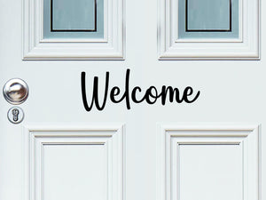 Front door decal that says, ‘Welcome’ in a script font on a front porch door. 