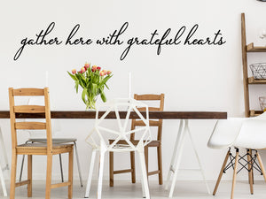 Wall decals for kitchen that say ‘Gather Here With Grateful Hearts’ in a cursive font on a kitchen wall.