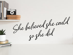 Wall decal for the office that says ‘She Believed She Could So She Did’ in a cursive font on an office wall.
