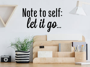 Decorative wall decal that says ‘Note To Self Let It Go’ on an office wall.