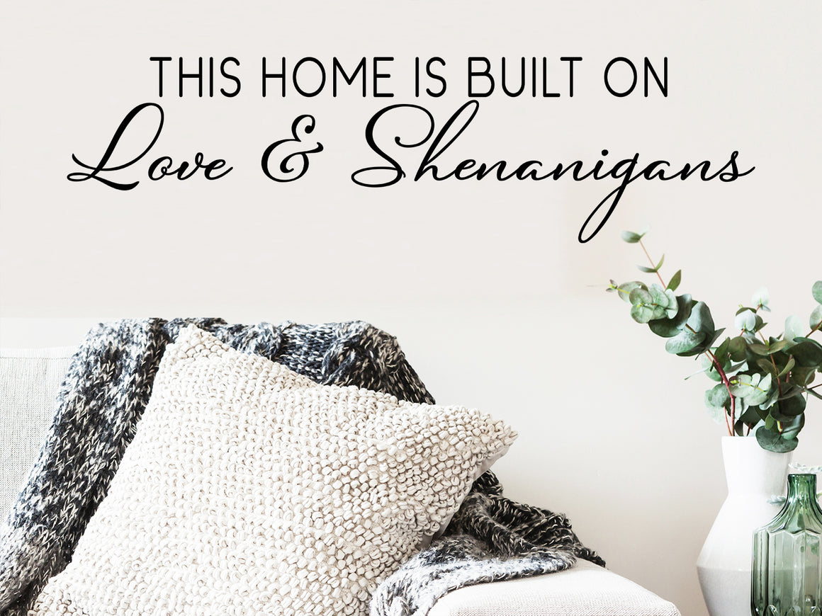 Living room wall decals that say ‘this home is built on love & shenanigans’ on a living room wall. 