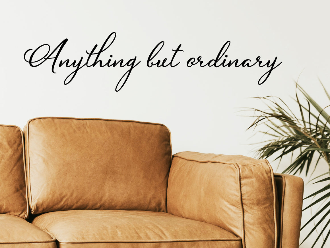 Living room wall decals that say ‘Anything But Ordinary’ in a cursive font on a living room wall. 