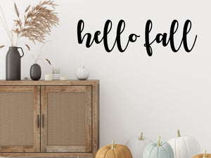 Living room wall decals that say ‘Hello Fall’ in a cursive font on a living room wall. 