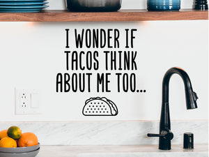 Decorative wall decal that says ‘I Wonder If Tacos Think About Me Too’ on a kitchen wall.