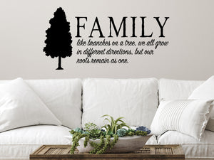 Living room wall decals that say ‘Family Like Branches On A Tree’ in a cursive font on a living room wall. 