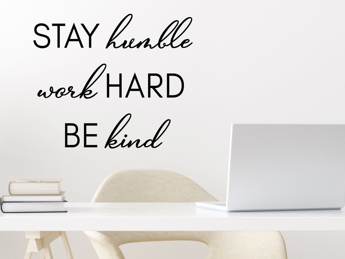 Wall decal for the office that says ‘Stay Humble Work Hard Be Kind’ in a script font on an office wall.
