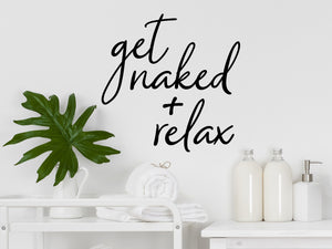 Wall decals for bathroom that say ‘Get Naked and Relax’ in a cursive font on a bathroom wall.