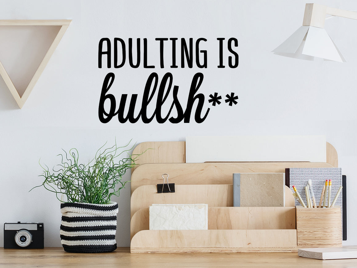 Decorative wall decal that says ‘Adulting Is Bullsh**’ on an office wall.