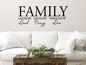 Living room wall decals that say ‘Family A Little Bit Loud A Little Bit Crazy & A Whole Lot Of Love’ in a cursive font on a living room wall. 