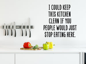 Decorative wall decal that says ‘I Could Keep This Kitchen Clean If You People Would Just Stop Eating Here’ on a kitchen wall.