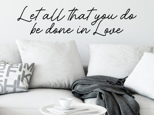 Living room wall decals that say ‘Let all that you do be done in Love’ in cursive font on a living room wall. 
