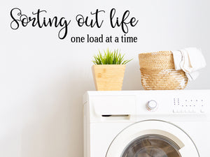 Laundry room wall decal that says ‘sorting out life one load at a time’ in a cursive font on a laundry room wall.