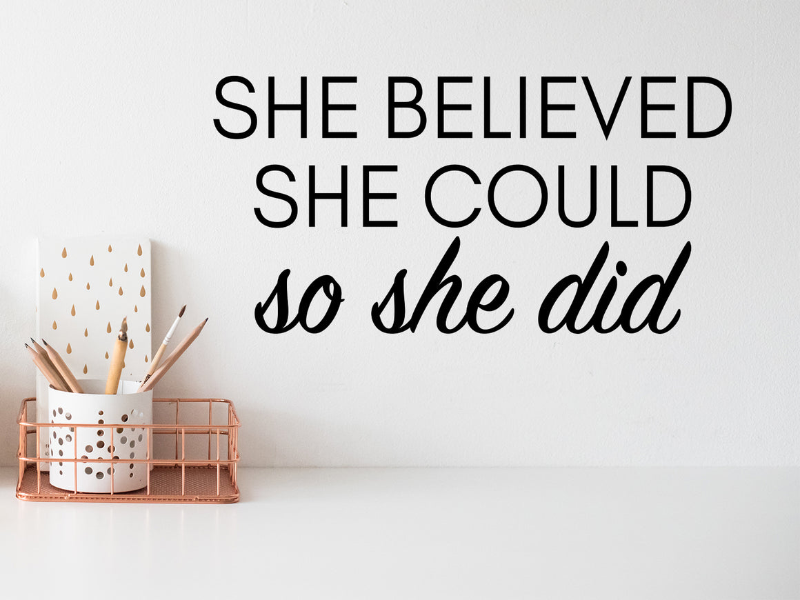 Wall decal for the office that says ‘She Believed She Could So She Did’ in a bold font on an office wall.
