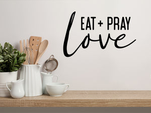 Wall decals for kitchen that say ‘Eat Pray Love’ in a bold font on a kitchen wall.