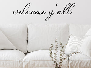 Living room wall decals that say ‘Welcome Y'all’ in a cursive font on a living room wall. 