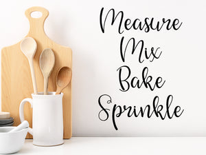 Decorative wall decal that says ‘Measure Mix Bake Sprinkle’ on a kitchen wall.