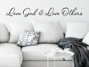Living room wall decals that say ‘Love god & love others’ in cursive on a living room wall. 
