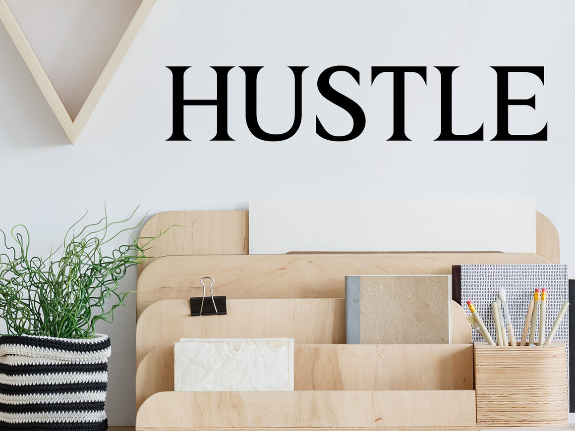 Wall decal for the office that says ‘Hustle’ in a print font on an office wall.