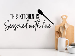 Wall decals for kitchen that say ‘This Kitchen Is Seasoned With Love’ in a script font on a kitchen wall.