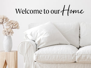 Living room wall decals that say ‘Welcome To Our Home’ in a script font on a living room wall. 