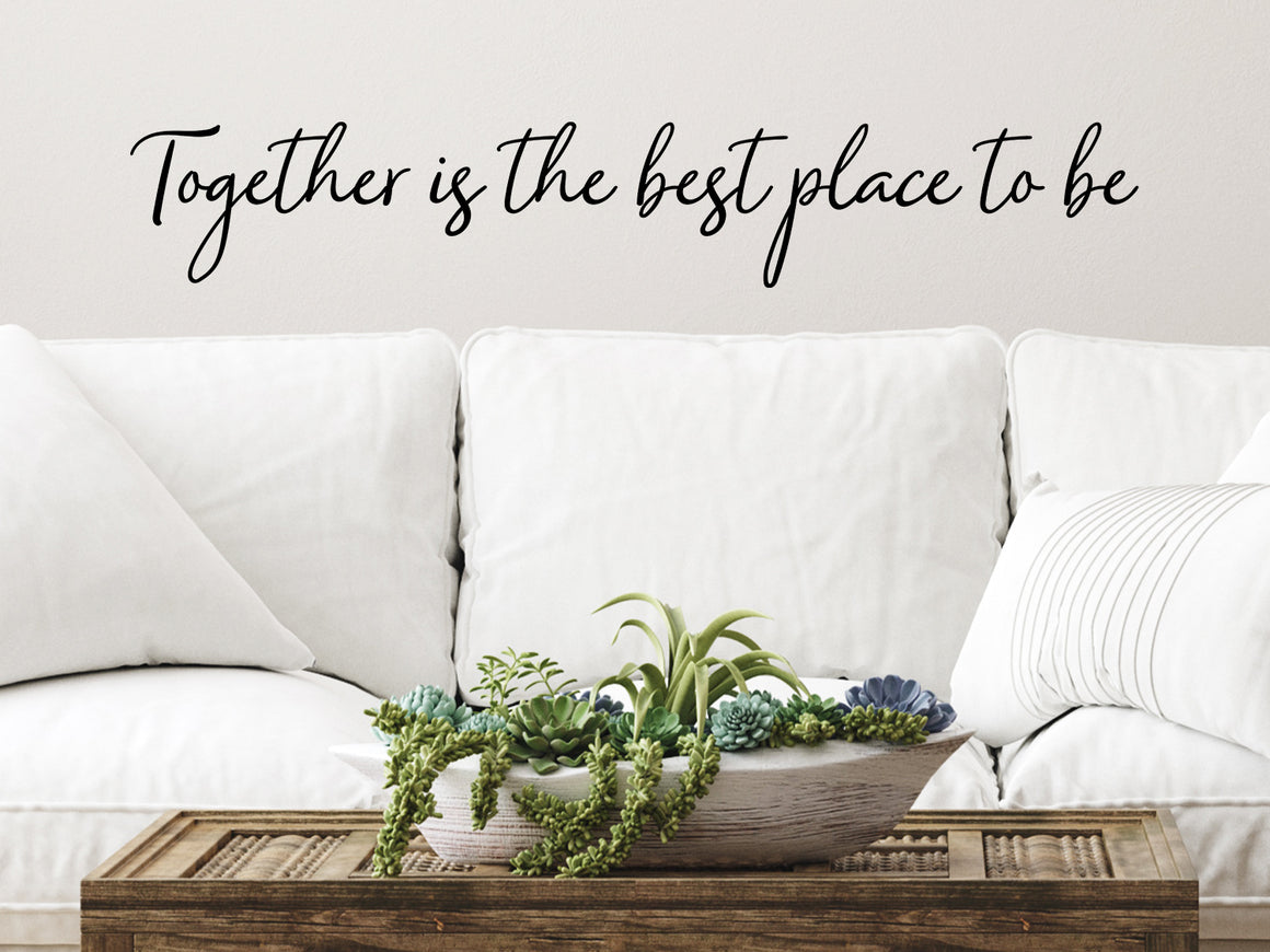 Living room wall decals that say ‘Together Is The Best Place To Be’ in a cursive font on a living room wall. 