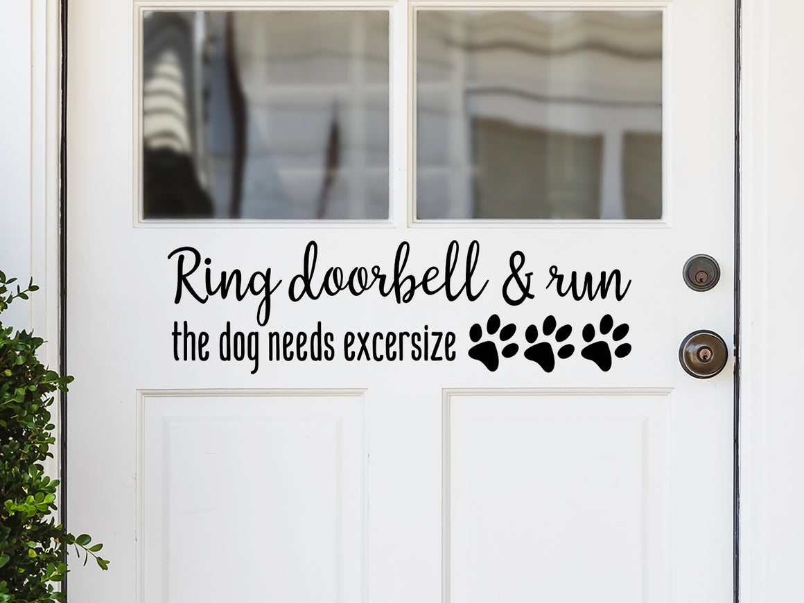 Front door decal that says, ‘Ring doorbell & run the dog needs exercise’ in a script font on a front porch door. 