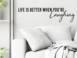 Living room wall decals that say ‘Life Is Better When You're Laughing’ in a bold font on a living room wall. 