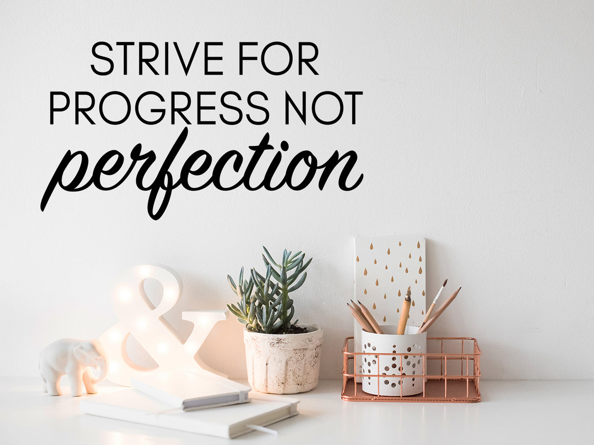 Wall decal for the office that says ‘Strive For Progress Not Perfection’ in a bold font on an office wall.