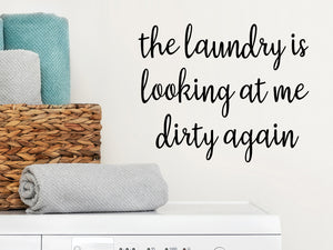 Decorative wall decal that says ‘The Laundry Is Looking At Me Dirty Again’ on a laundry room wall.
