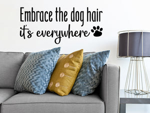 Living room wall decals that say ‘Embrace the dog hair it's everywhere’ with the image of a dog paw on a living room wall. 