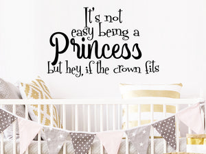 Wall decal for kids that says ‘It's not easy being a princess but hey, if the crown fits' on a kid’s room wall. 