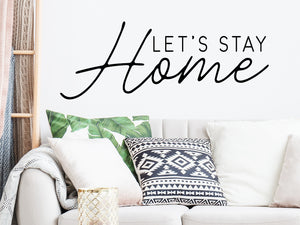 Living room wall decals that say ‘Let's stay home’ on a living room wall. 
