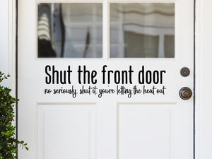 Front door decal that says, ‘shut the front door no seriously shut it you're letting the heat out’ on a front porch door. 