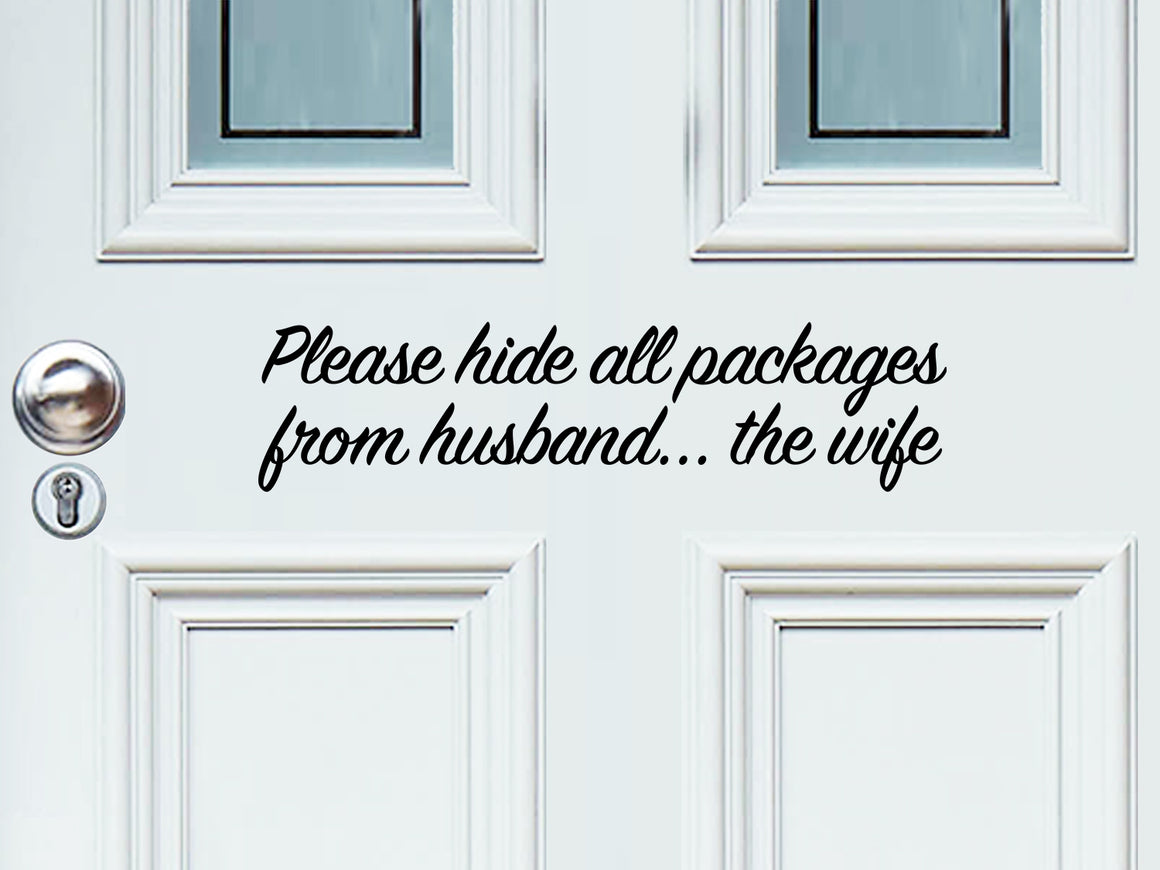 Front door decal that says, ‘Please Hide All Packages From Husband… The Wife’ in a cursive font on a front porch door.