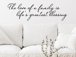 Living room wall decals that say ‘The Love Of A Family Is Life's Greatest Blessing’ in a cursive font on a living room wall. 
